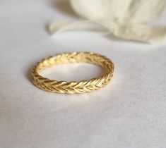 a gold ring sitting on top of a white surface next to a flower and leaf