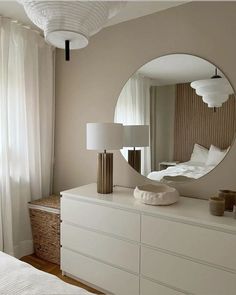 a white dresser topped with a mirror next to a window covered in curtains and pillows