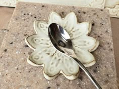 a spoon sitting on top of a white flower shaped plate