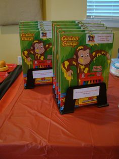 four children's books are on a table with orange cloths and plastic cups