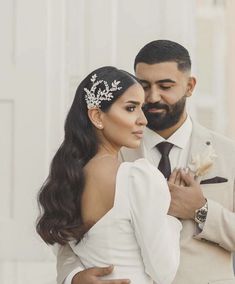 a man in a suit and tie standing next to a woman wearing a tiara