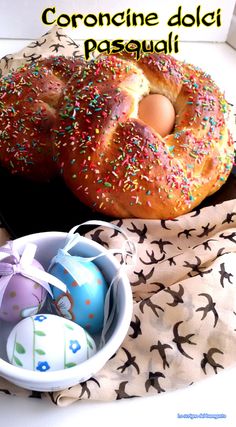 two donuts with sprinkles are next to an easter egg in a bowl