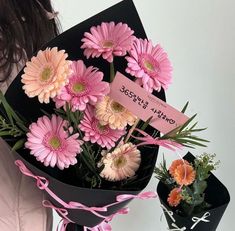 a woman holding a bouquet of pink and orange flowers in her hand with a price tag on it