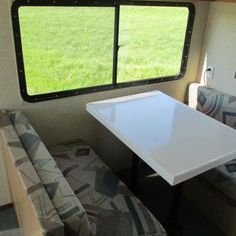 a table and couch in the back of an rv with grass out front on either side