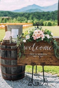 a wooden sign with flowers and greenery on it sitting next to a wine barrel