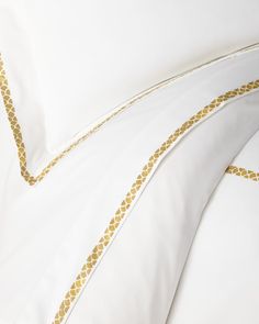 white and gold bedding with decorative lines on the pillowcase, along with two pillows