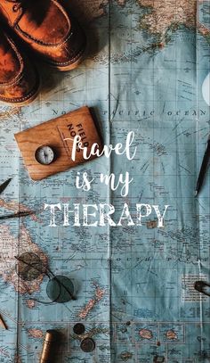 the words travel is my therapy on top of a map with shoes and other items