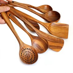 wooden spoons with holes in them being held by someone's hand