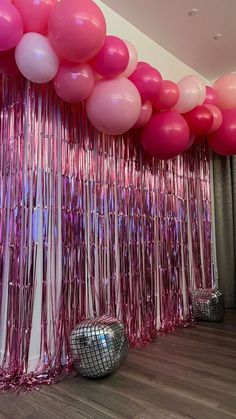 balloons and streamers are hanging from the ceiling in front of a wall with disco balls