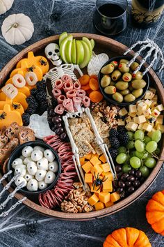 a platter filled with halloween food and snacks on top of a table next to two pumpkins