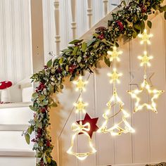 christmas decorations on the stairs with lights and greenery hanging from it's sides