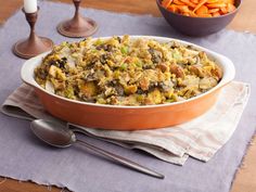 a casserole dish with carrots and other food on the table next to it