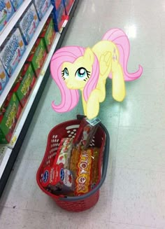 a shopping basket with candy in it on the floor next to a store display shelf