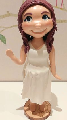 a small figurine of a girl in a white dress on a wooden stand