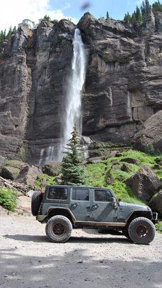 a jeep parked in front of a waterfall