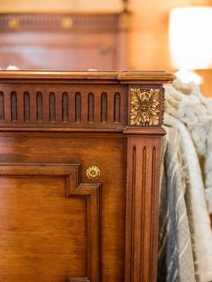 a bed with a wooden headboard next to a night stand and blanket on top of it