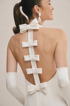 the back of a woman wearing white gloves and a bow tie