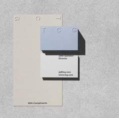 two business cards sitting on top of each other in front of a gray wall and floor