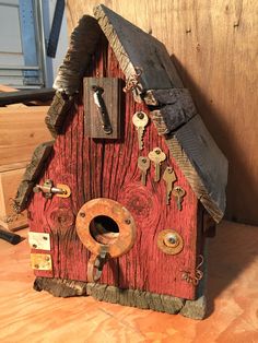 a red birdhouse with lots of keys attached to it's roof and door