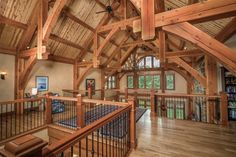 the inside of a house with wooden beams and wood flooring, windows, and railings