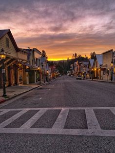 a street lined with small buildings under a cloudy sky at sunset in an old town