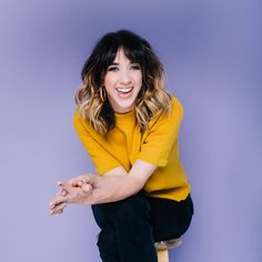 a smiling woman sitting on top of a stool