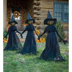 three black witches walking in front of a log cabin with pumpkins on the ground