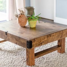 a wooden coffee table sitting on top of a carpeted floor next to a potted plant