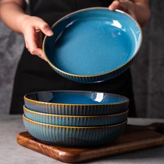 a person holding a blue dish over three bowls