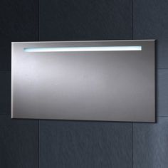 a bathroom mirror mounted to the side of a wall with an illuminated strip above it