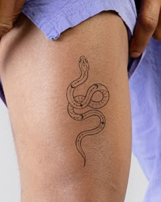 a woman with a tattoo on her thigh shows off the side of her leg that has a snake drawn on it