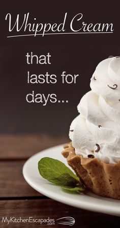 a white plate topped with whipped cream on top of a wooden table next to a green leaf