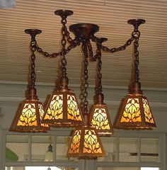 a chandelier with four lights hanging from it's sides and two lamps on each side