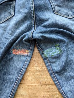 an old pair of jeans with patches on the back and sides, sitting on a wooden floor