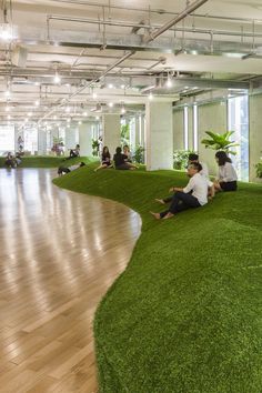 people sitting on the ground in an office building with artificial grass covering the floor and walls