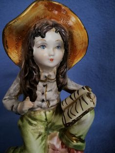 a ceramic figurine with a hat on it's head and hands in her lap