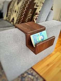 a wooden shelf on the back of a couch with a magazine holder attached to it