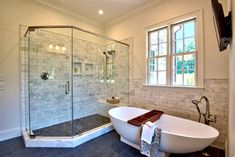 a bathroom with a claw foot bathtub next to a walk in shower and a large window