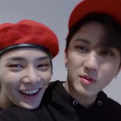 two young men with red hats on their heads and one is smiling at the camera