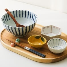 bowls and chopsticks are sitting on a wooden tray next to an empty bowl