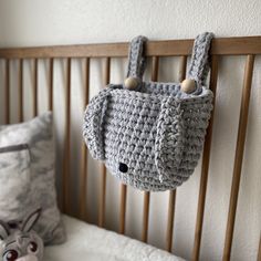 a crocheted purse hanging from the side of a wooden headboard next to a stuffed animal