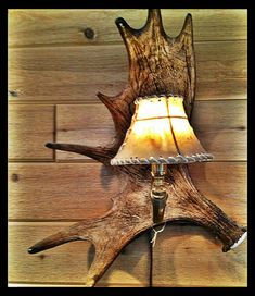 a lamp that is sitting on top of a wooden wall next to a deer's antler