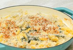 a blue casserole dish with cheese and spinach