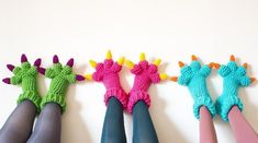 four crocheted dragon finger puppets are lined up in a row on a white surface