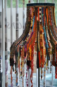 an assortment of scarves hanging from a lamp