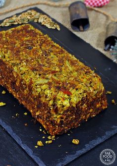 a large piece of food sitting on top of a black tray next to nuts and other items