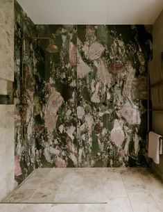 a bathroom with marble walls and flooring that has flowers on the wall, along with two shower heads