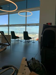 there are many chairs and luggage in this airport terminal area with large windows looking out onto the tarmac