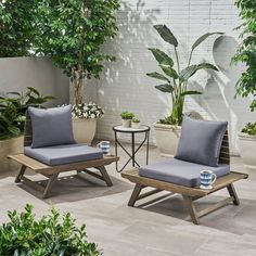 two lounge chairs sitting next to each other on top of a tiled floor near potted plants