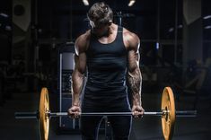 a man is holding a barbell in the gym